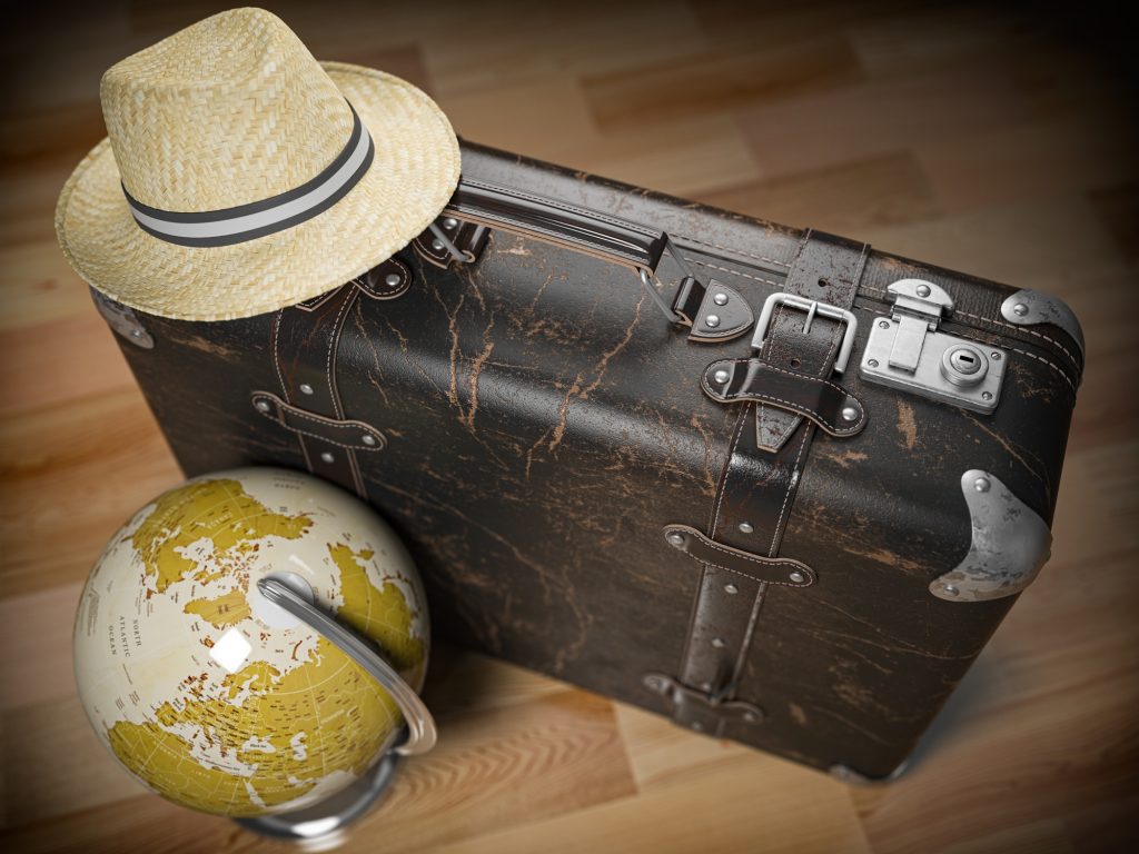 Tourism and travel concept. Globe and vintage suitcase with summer hat.